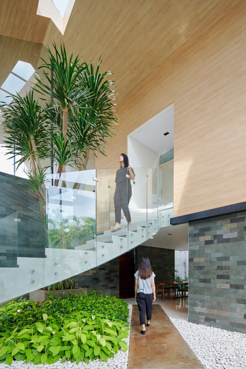 Cantilevered white staircase with glass balustrades and residents in motion near variegated stone walls