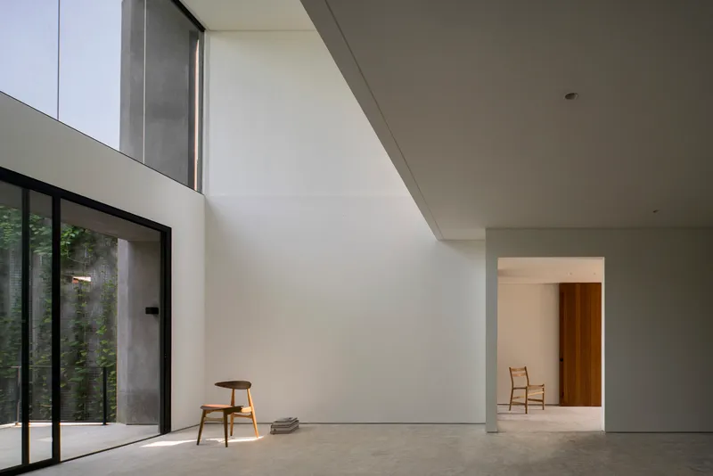 Interior corner with concrete floors and angled skylight casting soft shadows across white walls