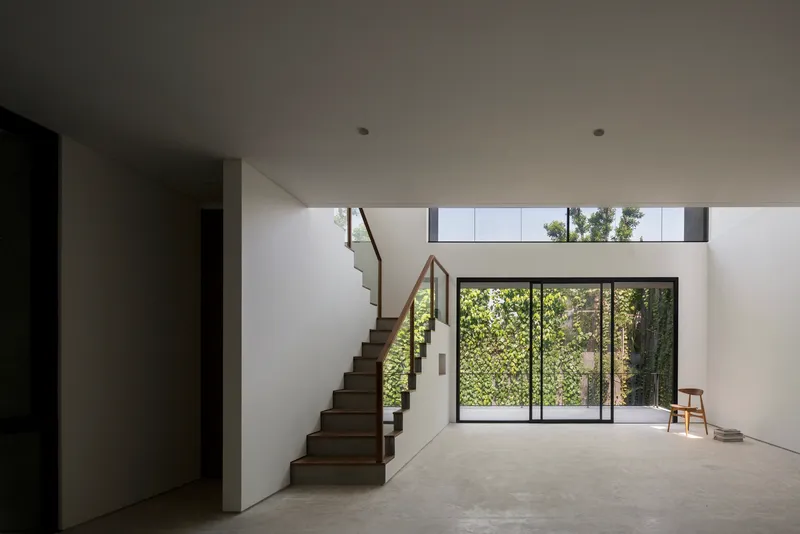 Open-plan living space with floating timber staircase and clerestory windows above courtyard glazing