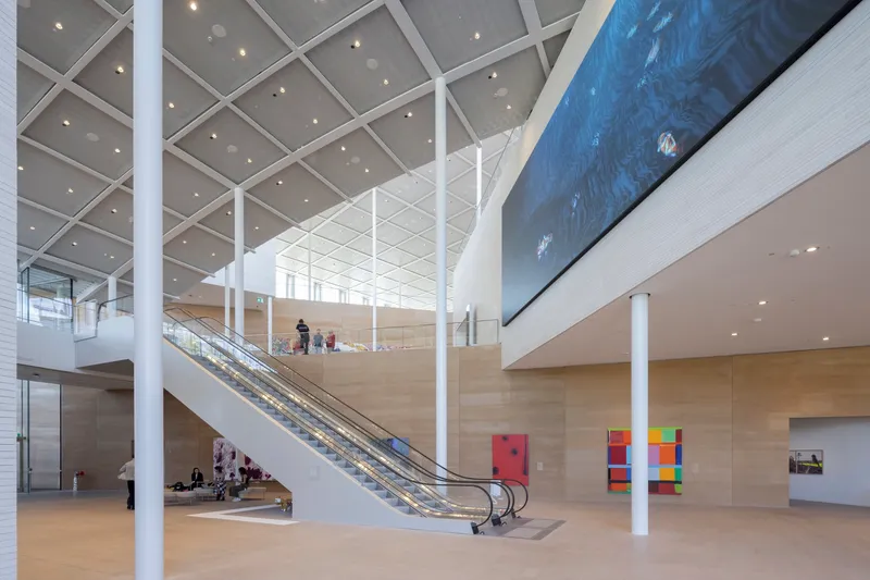 Multi-level atrium with escalators, white columns, and coffered ceiling under natural light