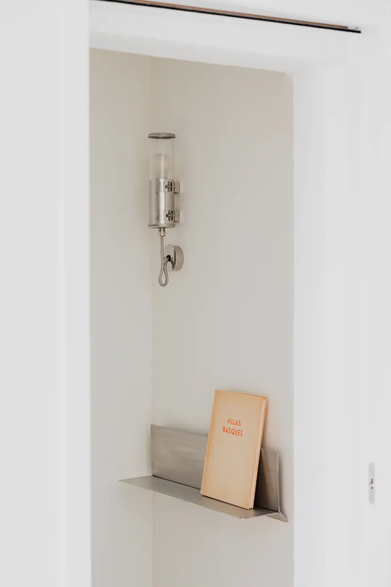 Built-in wall niche with glass sconce above and books on the ledge