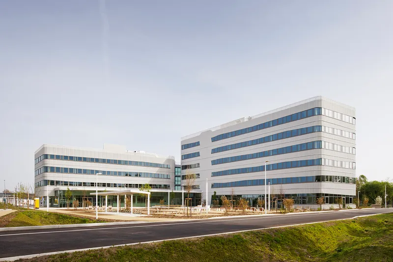Street view of two office buildings with horizontal banding of white cladding and blue-tinted glazing