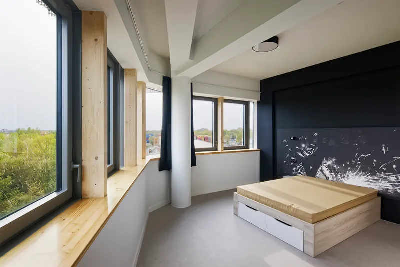 Corner room with exposed timber columns, polished concrete floor and a raised wooden platform bed