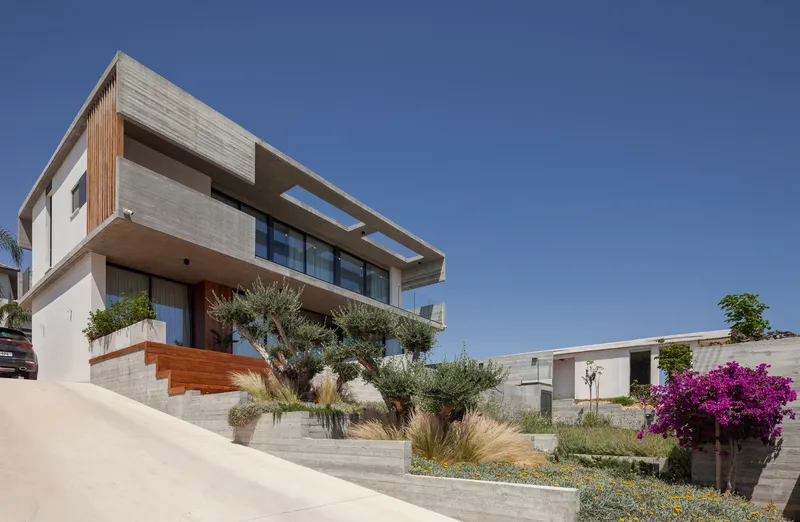 Street view of the board-formed concrete facade with cantilevered upper floor and terraced landscape