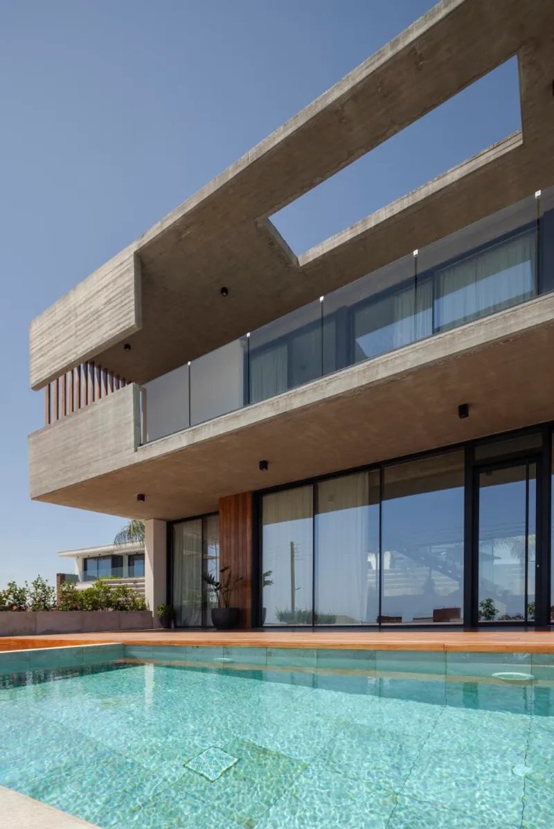 Rear terrace with pool showing the stacked concrete volumes and floor-to-ceiling glazing