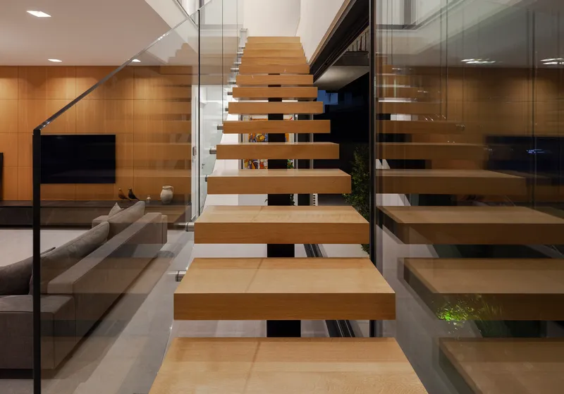 Floating timber treads with glass guardrails rising through the double-height living space