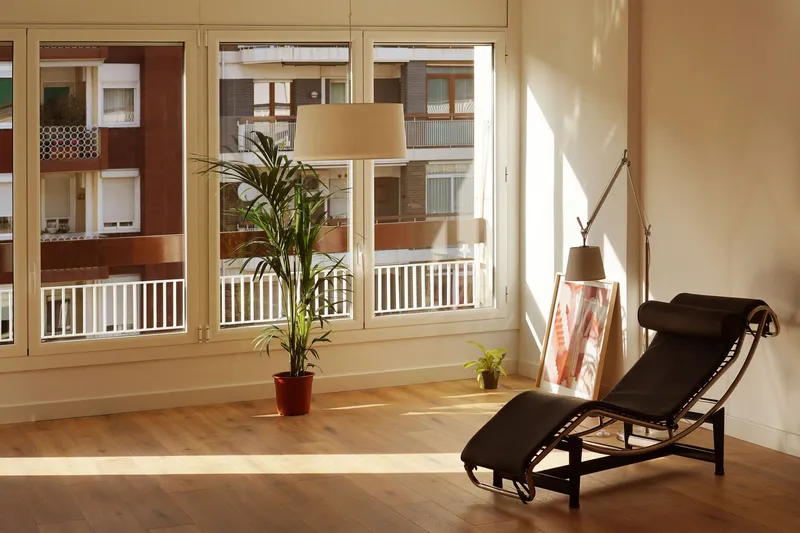 Interior corner with floor-to-ceiling windows overlooking a residential courtyard in afternoon sunlight