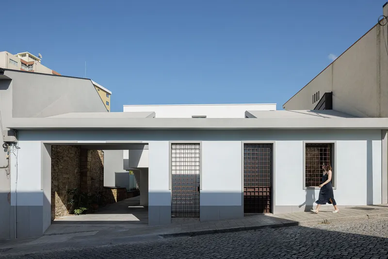 Street facade with white stucco and gridded metal screen doors beneath a clear blue sky