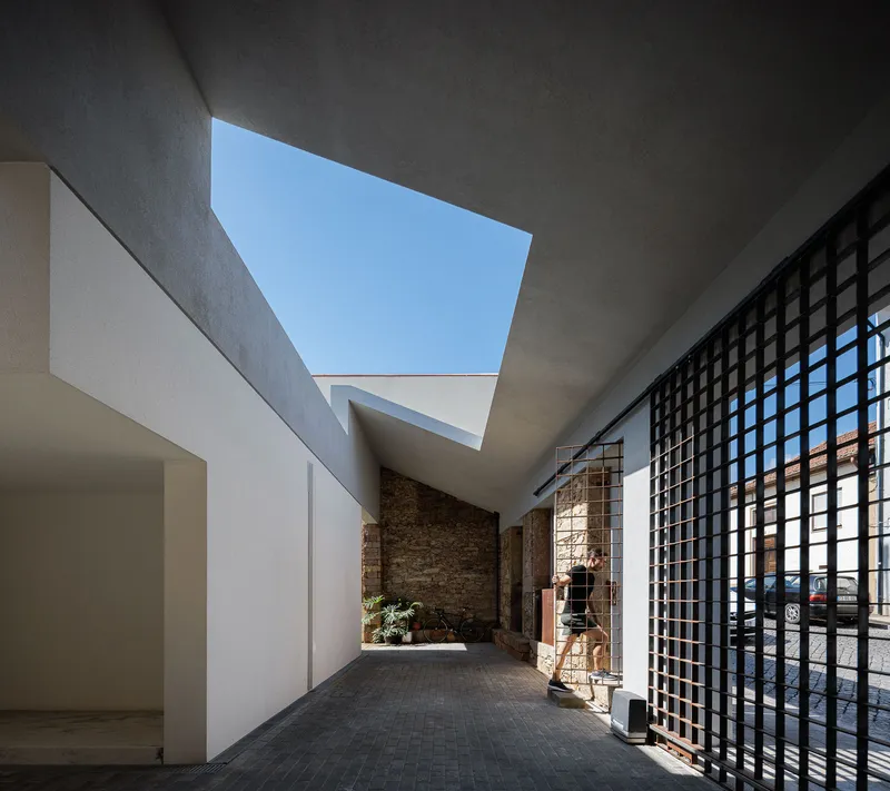 Covered passage with exposed brick wall and angled skylight casting shadows across the pavement