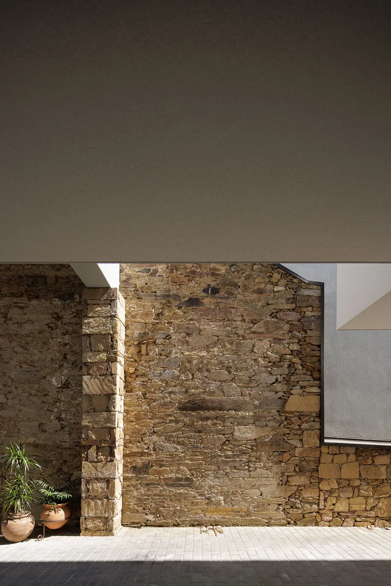 Narrow vertical slot of daylight illuminating a ruined stone wall beneath a canopy