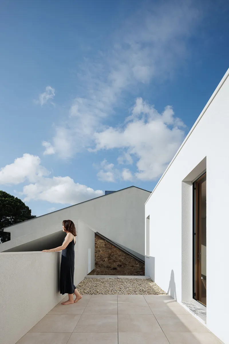 Rooftop terrace with gravel surface and woman in black dress under scattered afternoon clouds