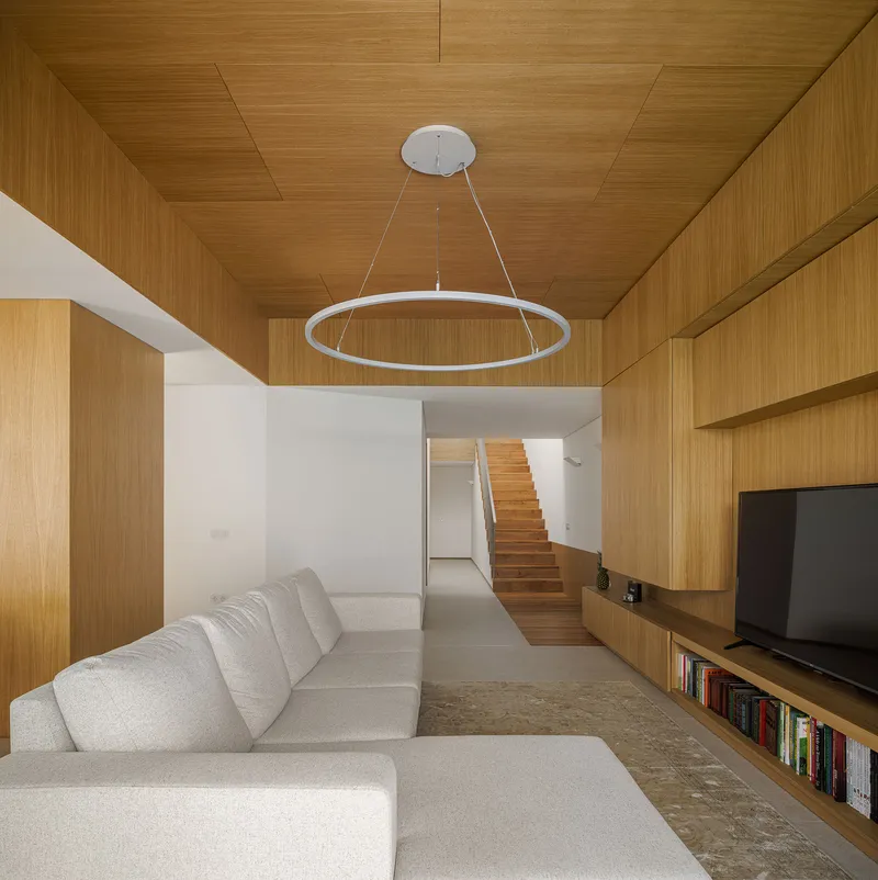 Living room with timber ceiling and wall panels framing a timber staircase in the background