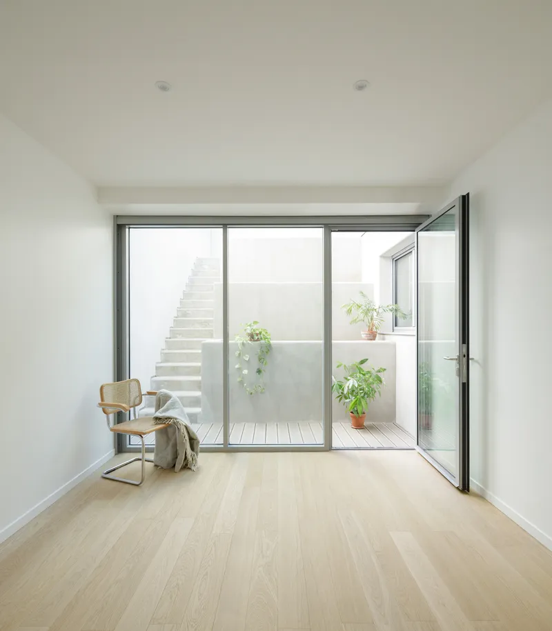 Room with glazed doors opening to a courtyard with timber decking, stair, and potted plants