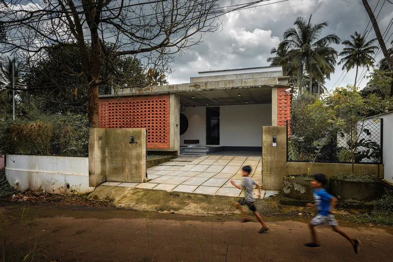Street view of the concrete entry portal with perforated brick screens as two children run past
