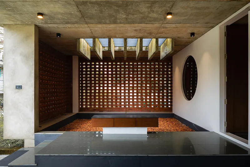 Interior courtyard with perforated brick wall, reflecting pool, and exposed concrete ceiling with clerestory openings