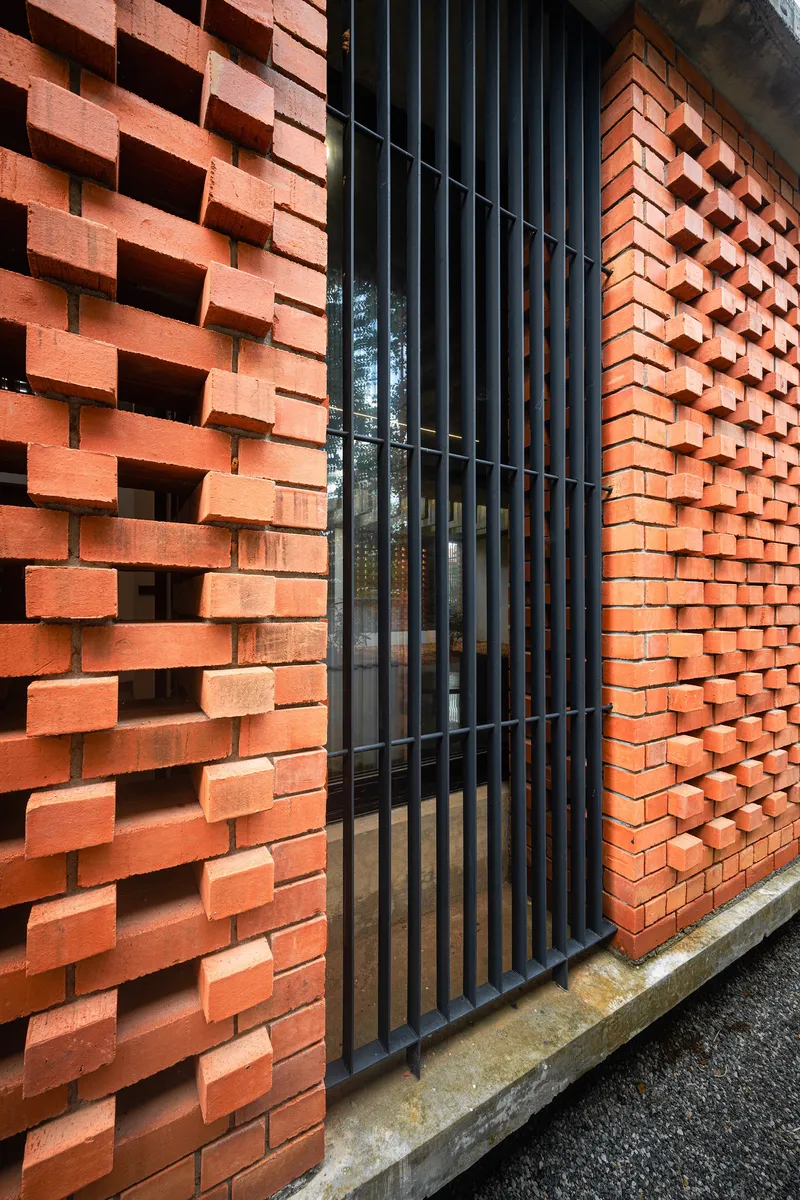 Close-up of the perforated brick screen wall and vertical metal slat gate casting shadow patterns