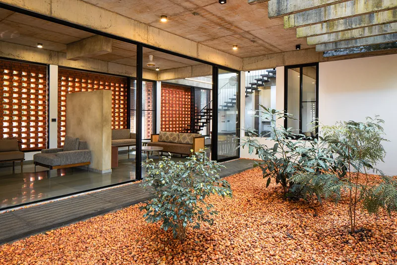 View across the planted courtyard showing glass walls opening to the interior living spaces and steel staircase