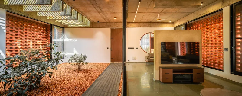 View from living area through glazing to the courtyard with gravel bed under dappled sunlight