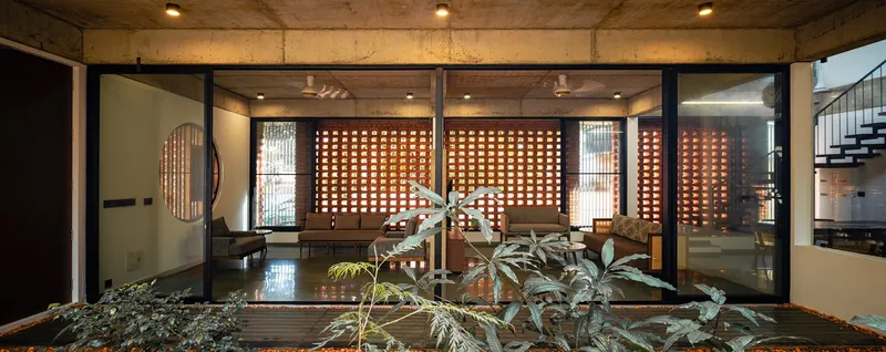 View across the courtyard showing perforated brick screens and interior rooms with polished concrete floors
