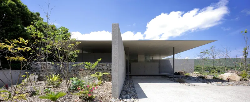 Entrance approach with cantilevered roof plane extending over concrete walls and gravel landscape beds