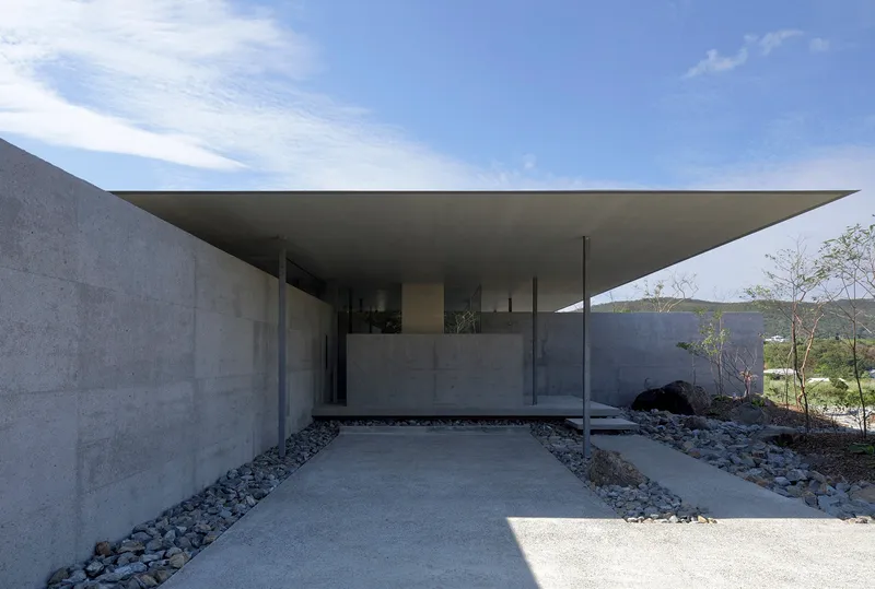 View along the carport showing slender steel columns supporting the hovering concrete roof slab