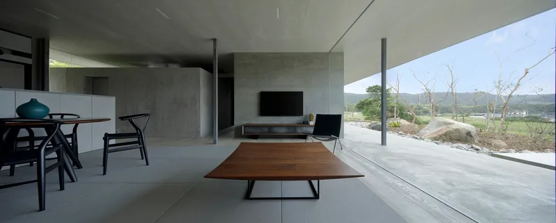 Interior view with walnut coffee table and glazed terrace overlooking low vegetation and distant hills