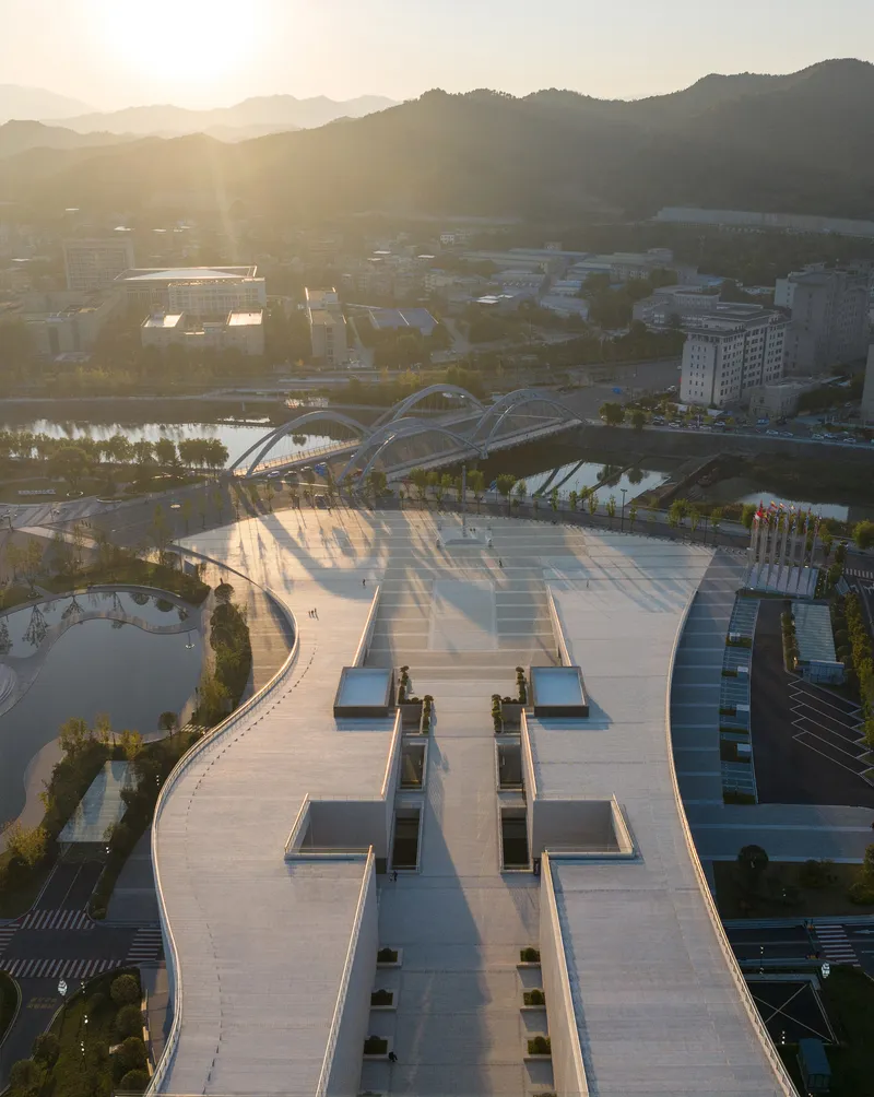 Aerial view of the stepped plaza with skylights at sunset, adjacent lake and mountains beyond