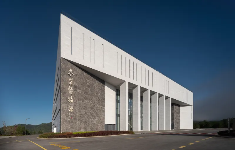 Street-level view of the white and stone facade with recessed colonnade under a clear blue sky