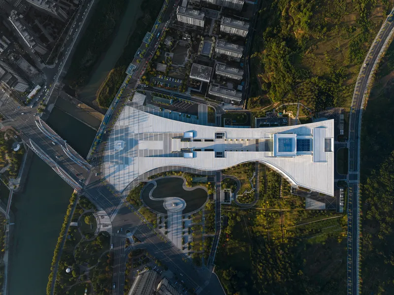 Overhead view of the white ribbed roof with curved skylights and landscaped ground plane below