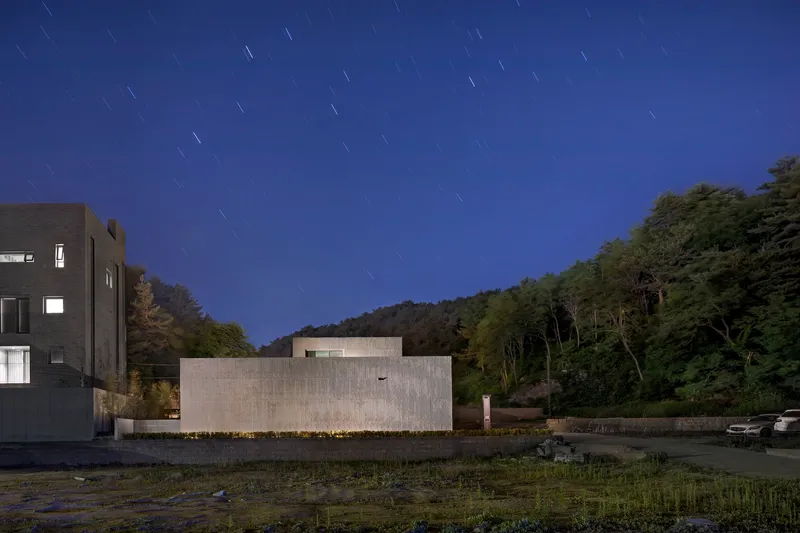 Long exposure of the ribbed concrete facade under a deep blue sky with star trails