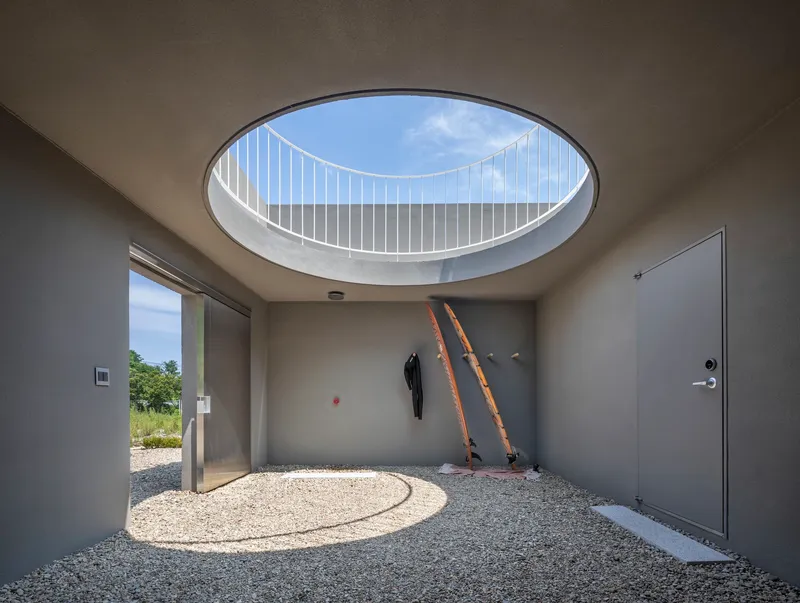 Interior courtyard with circular skylight framing white metal railing and wooden ladders against wall