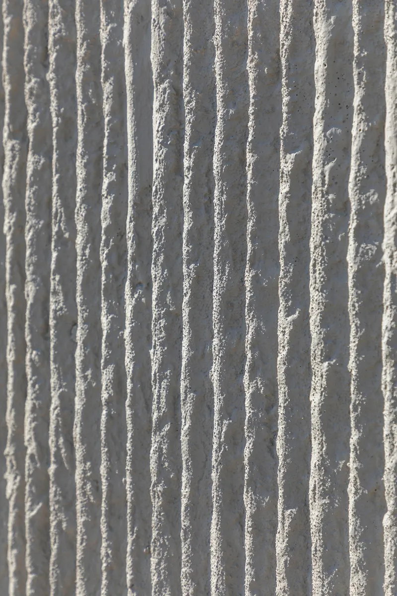 Close-up of vertical ribbed concrete surface showing textured formwork pattern in natural light