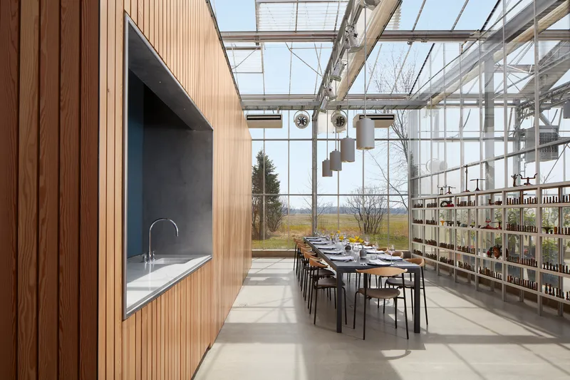 Dining area with long table set for a meal beneath the glazed roof with views to winter fields