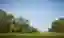 This image showcases a modern greenhouse set within a rural landscape. The greenhouse features a sym