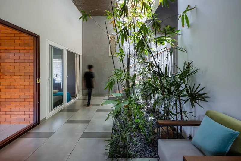 Ground floor passage with planted interior courtyard and figure in motion through doorway