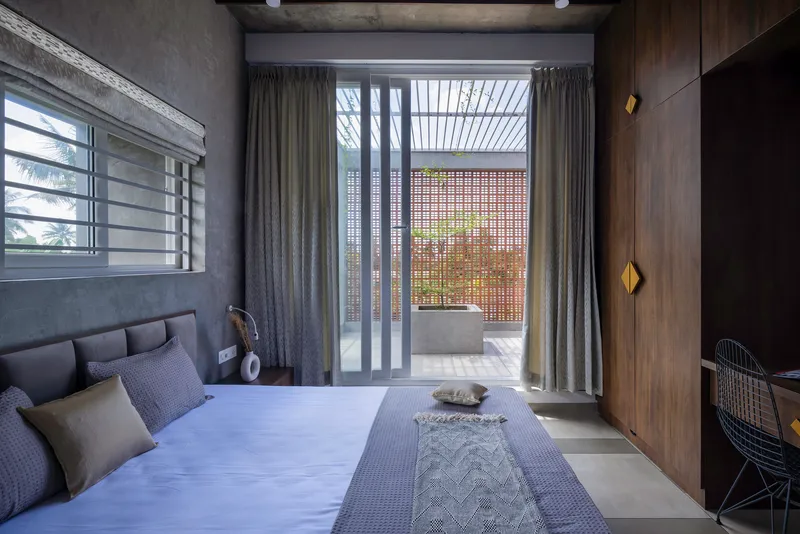 Bedroom looking toward a curtained opening with slatted screen beyond and perforated metal panel beyond
