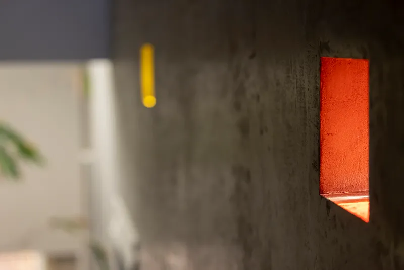 Close-up of an orange sconce set into a textured concrete wall