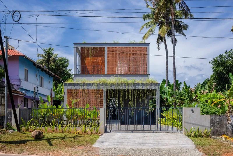 Street facade with woven bamboo screens and rooftop garden beneath palm trees and overhead power lines