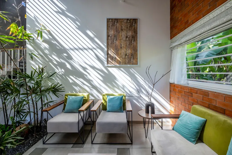 Seating area with striped shadow patterns from louvered skylight falling across white wall