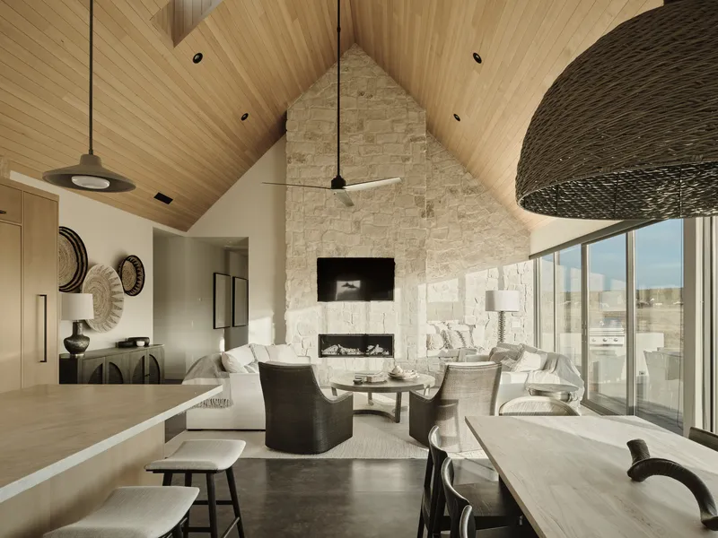 Living room with vaulted timber ceiling and stone fireplace wall under pendant fixtures