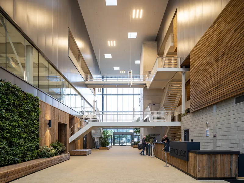 Interior atrium with timber-clad staircases, planted walls, and multiple connecting bridges
