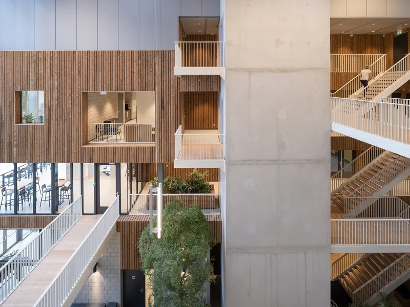 Interior atrium with planted terraces and vertical timber slat screens flanking a concrete core