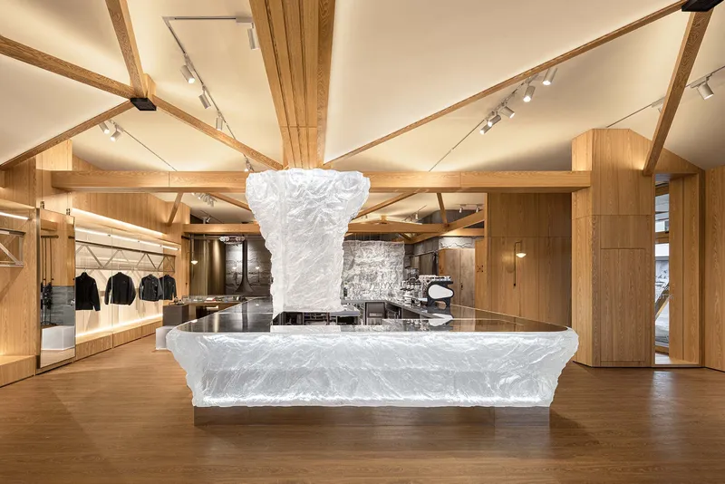 Sculptural white counter beneath radiating timber beams and a vaulted ceiling with track lighting