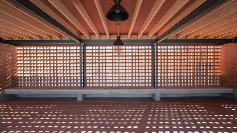 Long view of terracotta screen wall with timber ceiling joists and pendant lights overhead