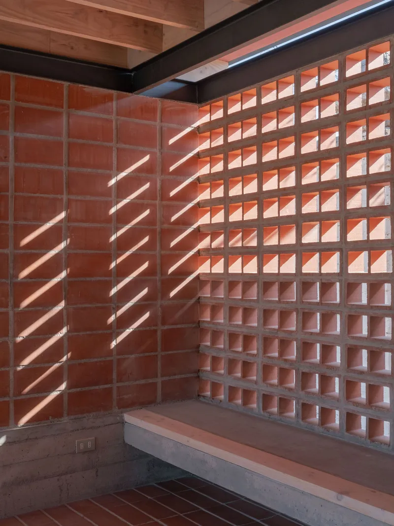 Interior corner with terracotta block walls and concrete bench casting diagonal shadows