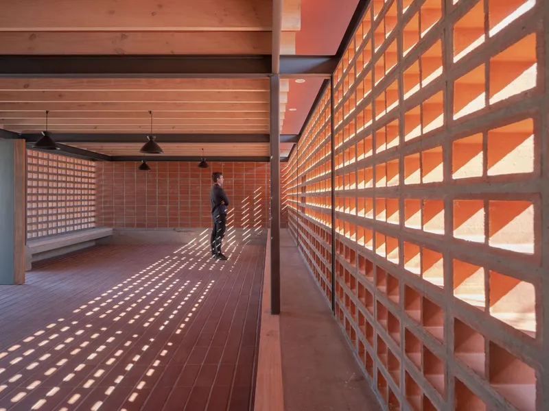 Interior corridor with terracotta block screen walls casting dappled shadows on timber decking