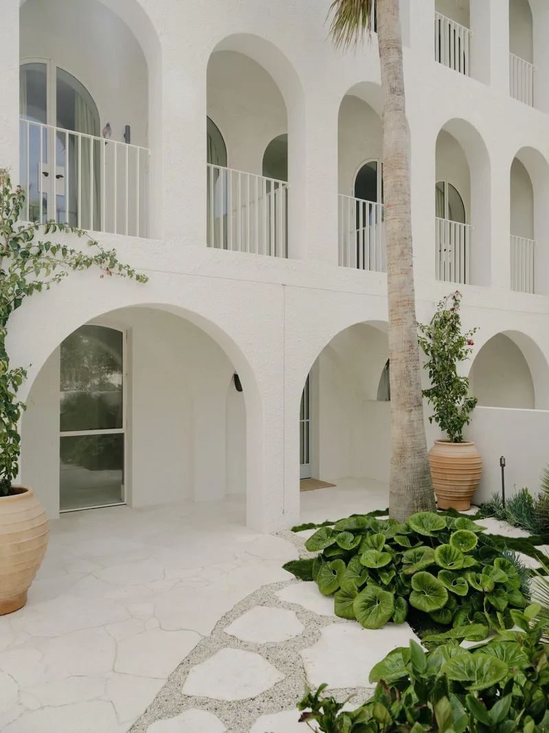 Interior courtyard with stone paving, palm trunk and terracotta planters under arcaded walkways