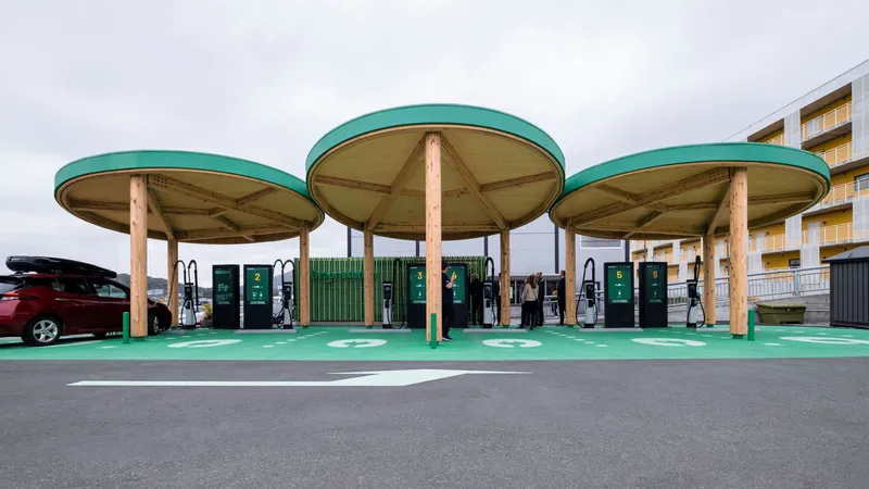 Three circular timber canopies with teal metal fascias sheltering electric vehicle charging stations under a cloudy sky