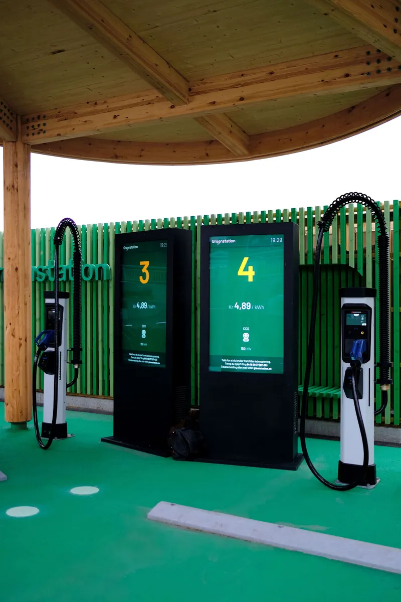 Electric vehicle charging stations beneath the timber canopy with green metal screening and rubber flooring