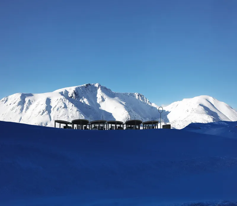 Low profile charging canopy silhouetted against snow-covered mountains and blue sky
